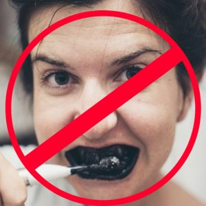 woman brushing teeth with charcoal toothpaste